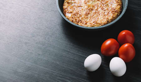 Spanish omelette on wood table, with eggs and tomatoesの写真素材