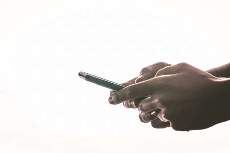 hands holding and texting in a smartphone with back light and copy spaceの写真素材