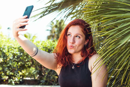 Caucasian woman taking a selfie with smartphone outdoors in parkの写真素材