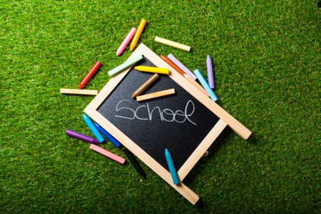 Top view of mini blackboard and colors on plastic grass background. Concept back to schoolの写真素材