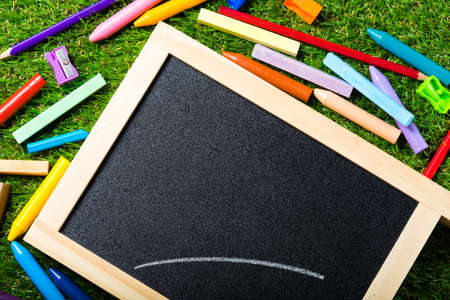 Top view of mini blackboard and colors on plastic grass background. Concept back to schoolの写真素材