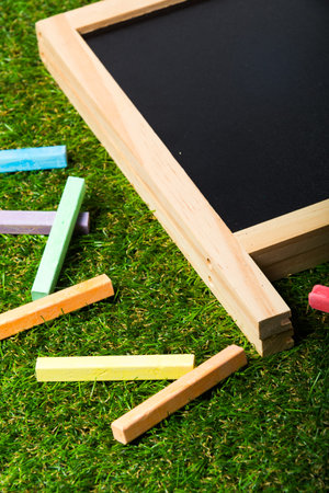 Top view of mini blackboard and colors on plastic grass background. Concept back to school