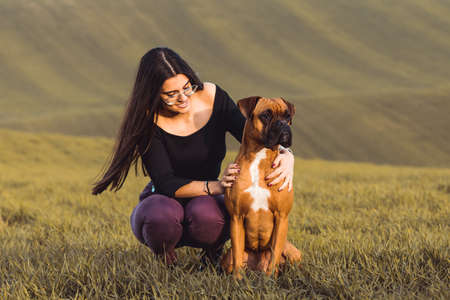 fashion girl with her boxer dog at the meadow in fallの写真素材