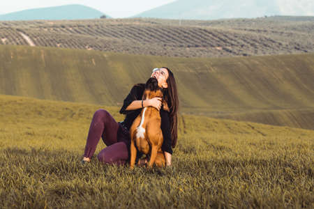 fashion girl with her boxer dog at the meadow in fallの写真素材