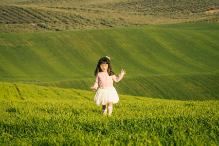 Little girl with pink shirt and skirt in a meadow. Disgusted face. she does not like the fieldの写真素材