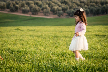 Little girl with pink shirt and skirt in a meadow. Disgusted face. she does not like the fieldの写真素材