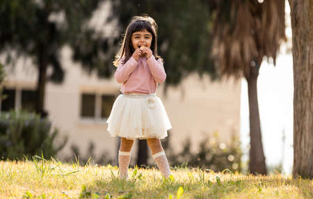 little girl eating sweets in a parkの写真素材