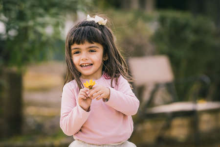 Little girl catching a flower in a park. Smiling and happy with a flower. Copy Spaceの写真素材