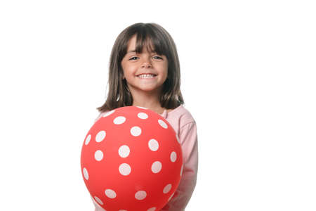 Brunette little girl smiling to camera with a balloon on white backgroundの写真素材