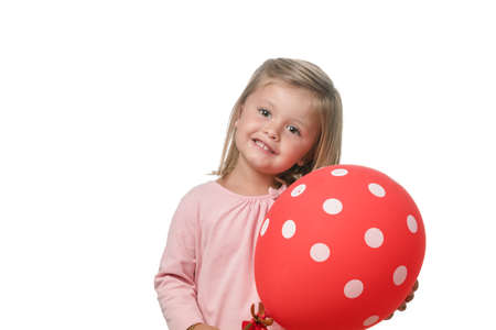 Blonde little girl smiling to camera with a balloon on white backgroundの写真素材