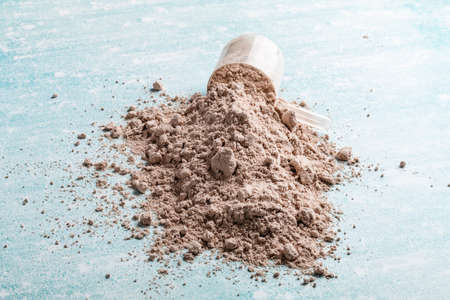 Protein powder in the measuring plastic spoon on blue backgroundの写真素材