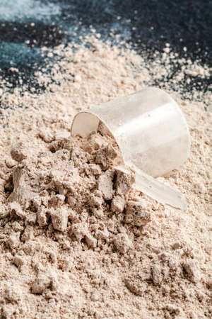 Protein powder in the measuring plastic spoon on dark backgroundの写真素材