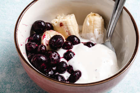 Yogurt with banana, blueberries and chocolate ready to eat in a bowlの写真素材