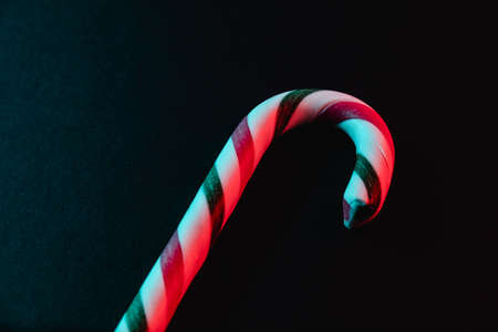Minimal Christmas composition. Greeting card template with candy cane on dark background.の写真素材