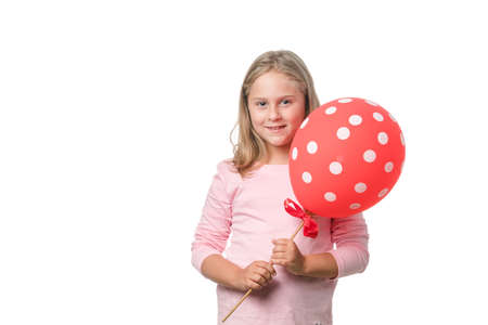 Blonde little girl smiling to camera with a balloon on white backgroundの写真素材