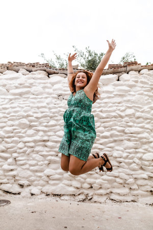 Young woman jumping and celebrating on the background of old brick wall.