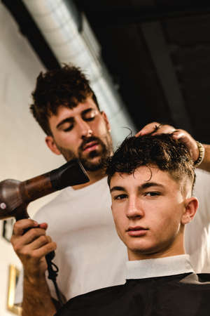 Confident teenager visiting hairstylist in barber shopの写真素材