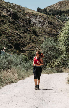 Active girl running at mountain, rural wayの写真素材