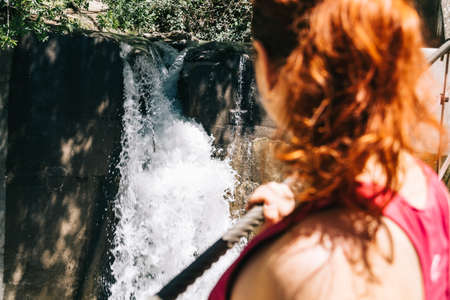 Woman on a bridge looking at the waterfall. Los Cahorros, Granada, Spainの写真素材