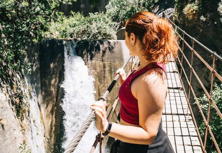 Woman on a bridge looking at the waterfall. Los Cahorros, Granada, Spainの写真素材