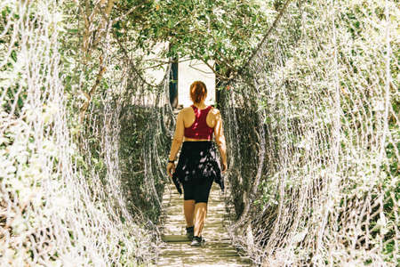 Young woman in black dress and hat looking around in tropical forestの写真素材