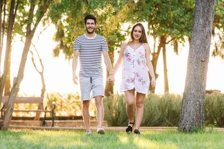 Happy pregnant couple walking at park and smilingの写真素材