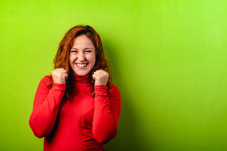 Expressive happy redhead woman on green background and copy spaceの写真素材