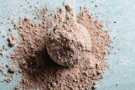 Protein powder in the measuring plastic spoon on blue backgroundの写真素材