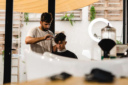 Confident teenager visiting hairstylist in barber shopの写真素材