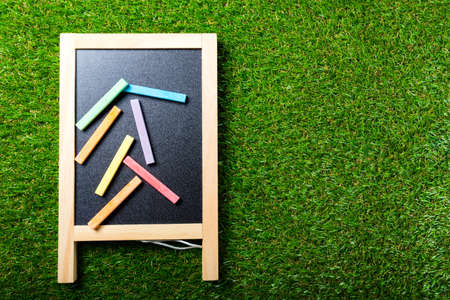 Top view of mini blackboard and colors on plastic grass background. Concept back to schoolの写真素材