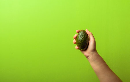 avocado in a hand of woman green background. healthy food concept