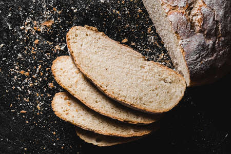 Sliced loaf of dark homemade bread dusted with flourの写真素材