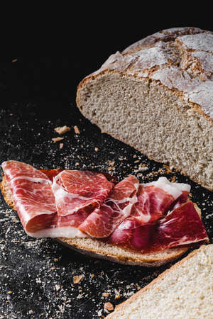 Slice of bread seasoned with serrano ham on darkの写真素材