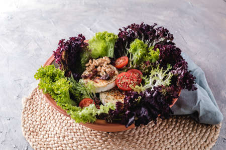 Salad with lettuce, cherry tomatoes, goat cheese, nuts and spicesの写真素材