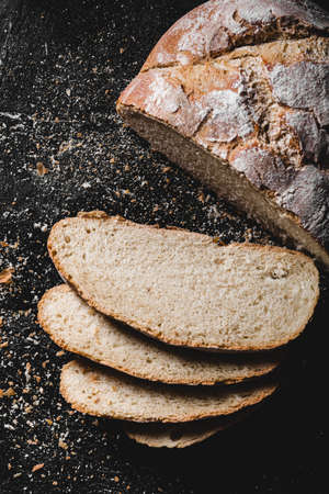 Sliced loaf of dark homemade bread dusted with flourの写真素材