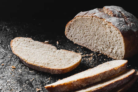 Sliced loaf of dark homemade bread dusted with flourの写真素材