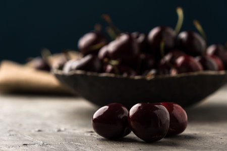 Ripe sweet cherry in ceramic bowl at concrete background