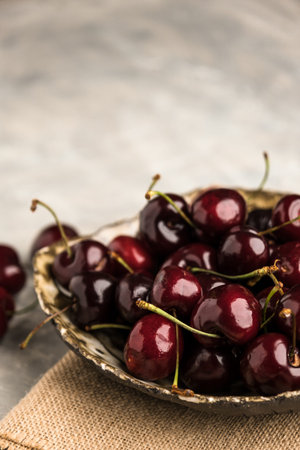 Ripe sweet cherry in ceramic bowl at concrete background