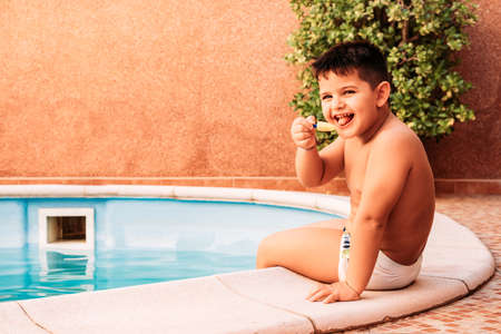 happy little boy in the pool while eating an ice creamの写真素材