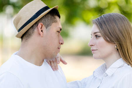 young couple looking into each others eyes in a park. Latin man and Caucasian womanの写真素材