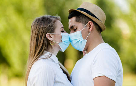 Couple with mask kissing at parkの写真素材