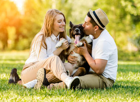 Lovely couple with their dog having fun in the parkの写真素材