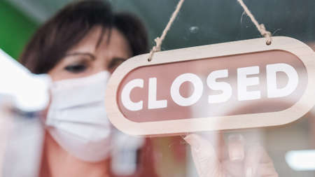 Woman turning a sign from open to closed.の写真素材