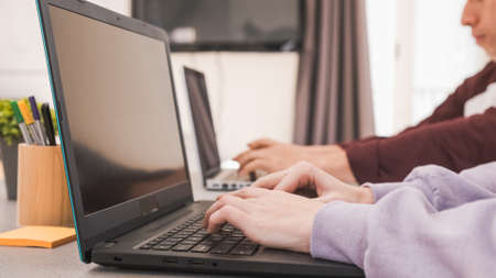 Unrecognizable man and woman using laptops while working remote from home.の写真素材