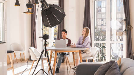 Young   bloggers creating content for a social media network making a video with a professional camera on a tripod at home.の写真素材