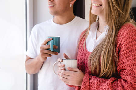 unrecognizable couple relaxing while having coffee and looking out the window at home.の写真素材