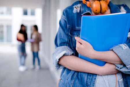 Close-up of a college student holding folders while standing at the hallway. Education concept.の写真素材