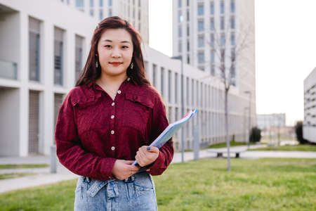 Portrait of an Asian student standing outdoors on college campus. Education concept.の写真素材