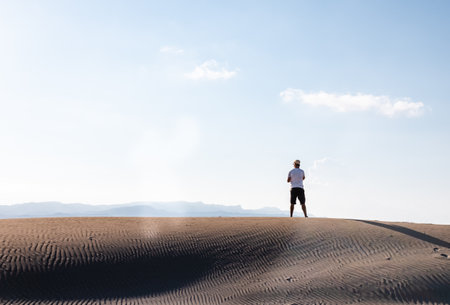 Man calling with a smart phone stand in the desert dunes alone. Copy spaceの写真素材