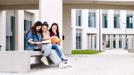 three asian girl students talking at break time sitting on campusの写真素材